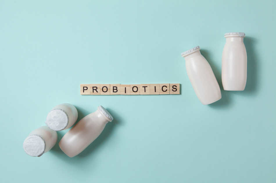 Bottles with probiotics and prebiotics dairy drink on light blue background. Bio yogurt with useful microorganisms. Production with biologically active additives. Fermentation and diet healthy food.