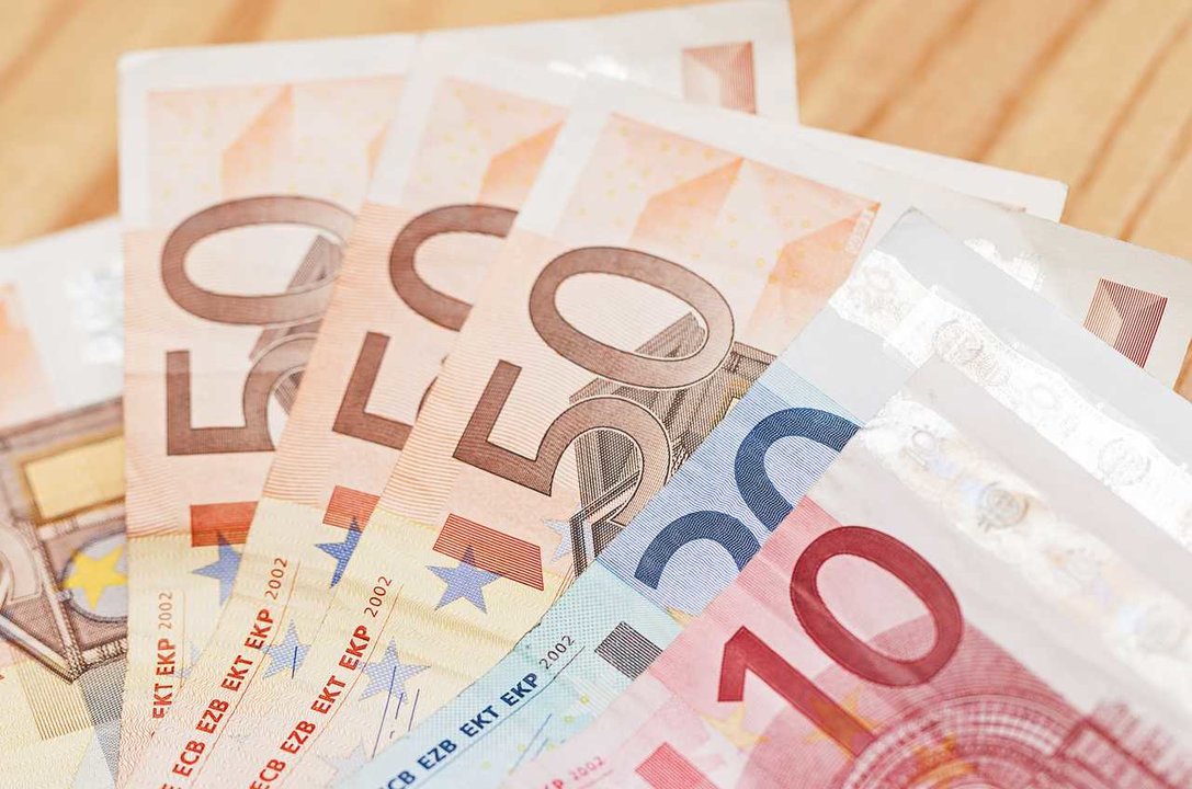 Heap of different euro banknotes on a wooden table