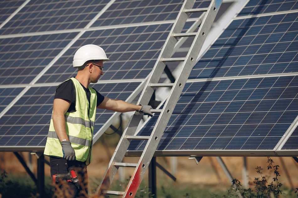 Engineer in a white helmet. Man near solar panel. Worker with a ladder